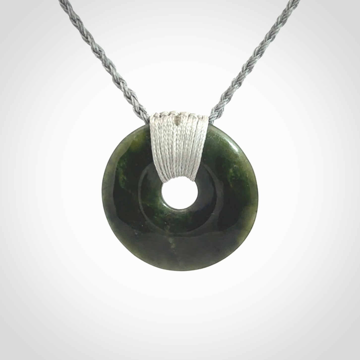 These are medium sized pendants - very finely carved. They are New Zealand Jade discs with a centre hole. It is suspended from a cord which is adjustable. These are beautiful pieces of expressive jade jewellery. Unique New Zealand made pendants for men and women. Perfect gifts for all.