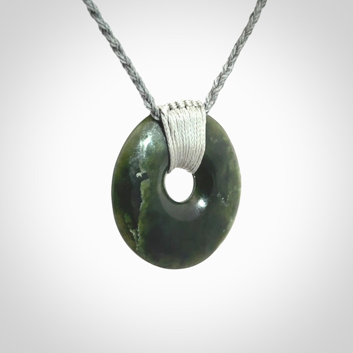 These are medium sized pendants - very finely carved. They are New Zealand Jade discs with a centre hole. It is suspended from a cord which is adjustable. These are beautiful pieces of expressive jade jewellery. Unique New Zealand made pendants for men and women. Perfect gifts for all.