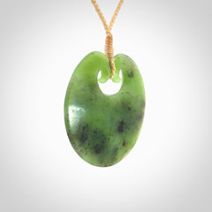 This picture shows a large contemporary pendant carved for us in New Zealand jade. The cord is a four-plait, adjustable beige coloured necklace.