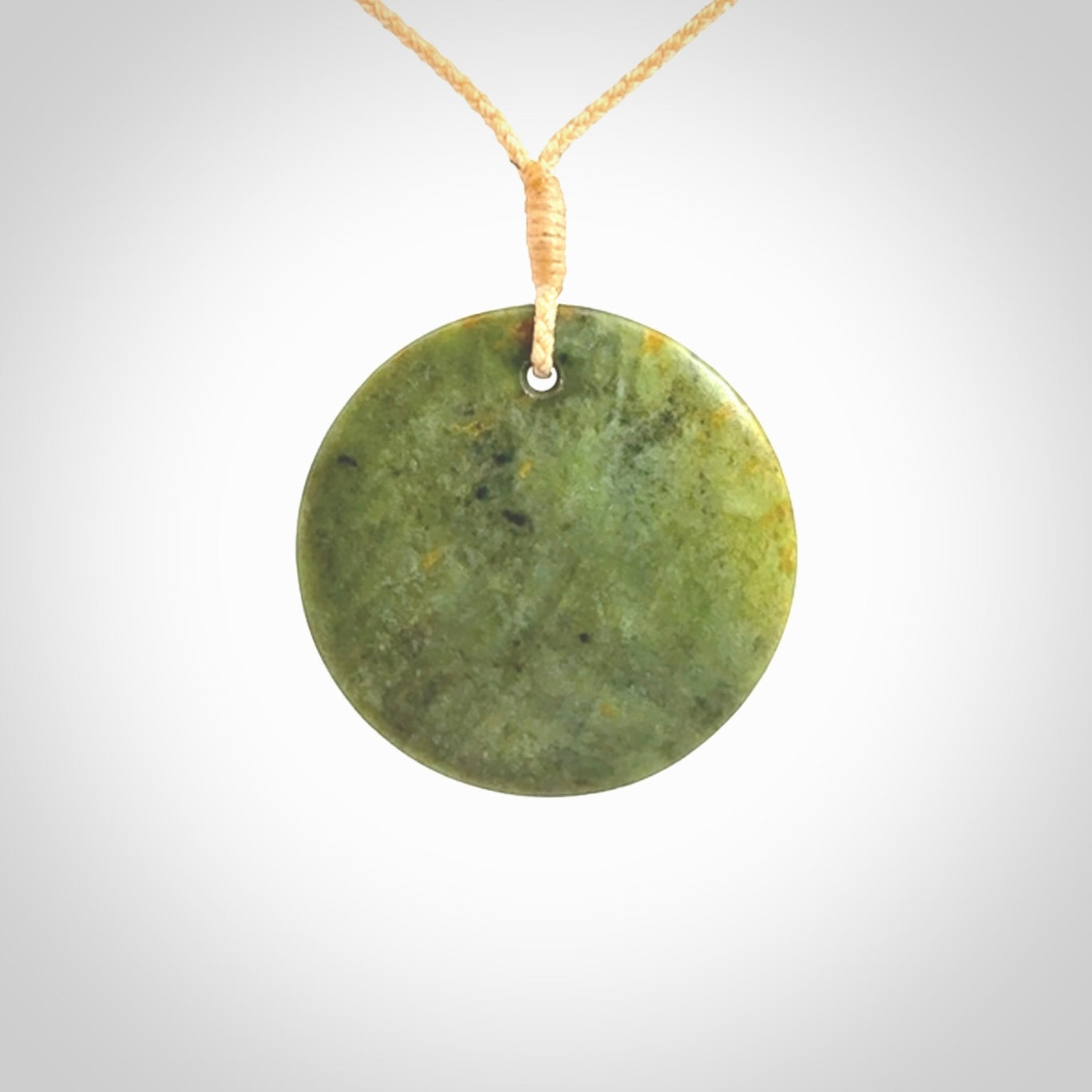 This piece is a medium sized, oval round, disc pendant. It is suspended on a beige coloured braided cord that is length adjustable.