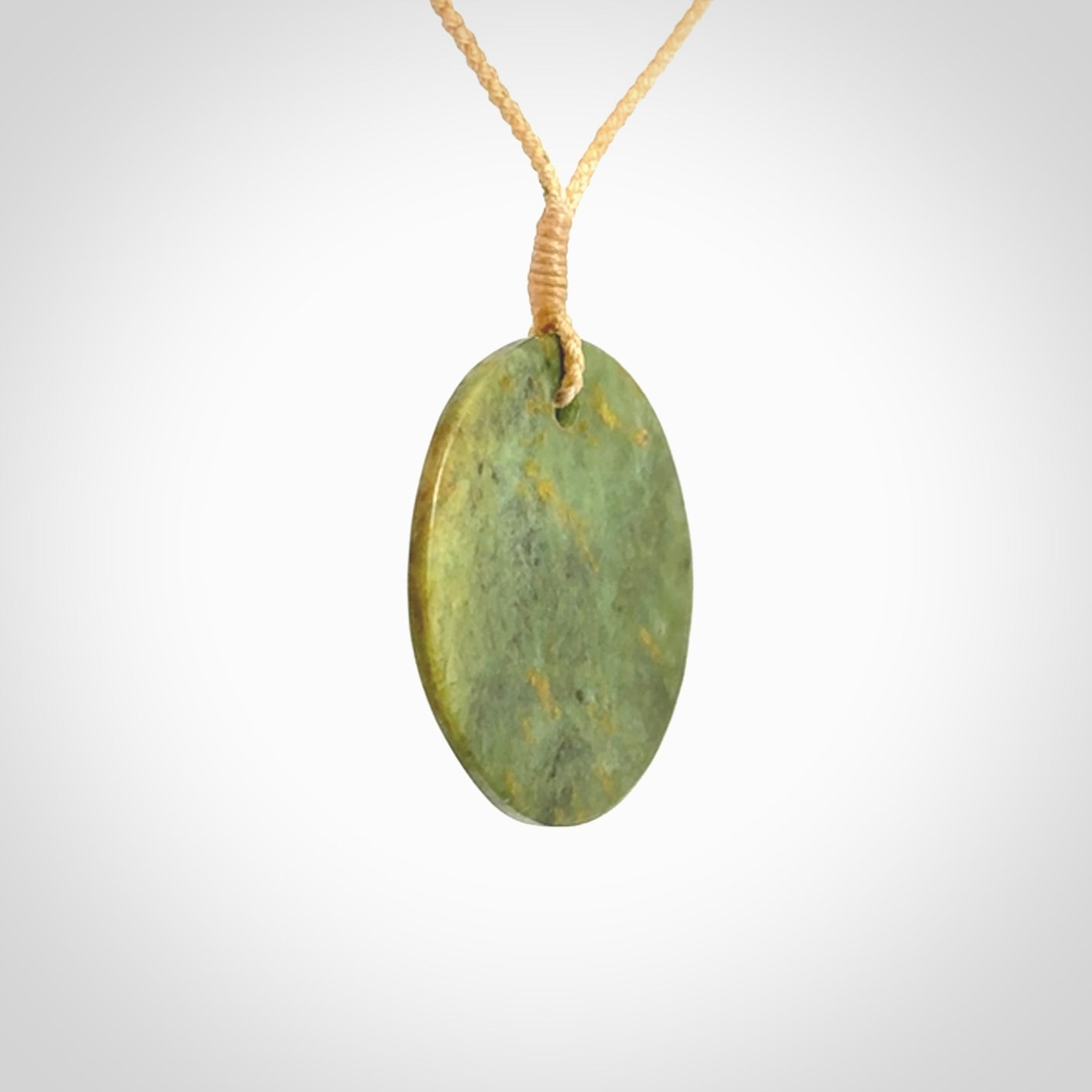 This piece is a medium sized, oval round, disc pendant. It is suspended on a beige coloured braided cord that is length adjustable.
