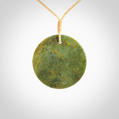 This piece is a medium sized, oval round, disc pendant. It is suspended on a beige coloured braided cord that is length adjustable.