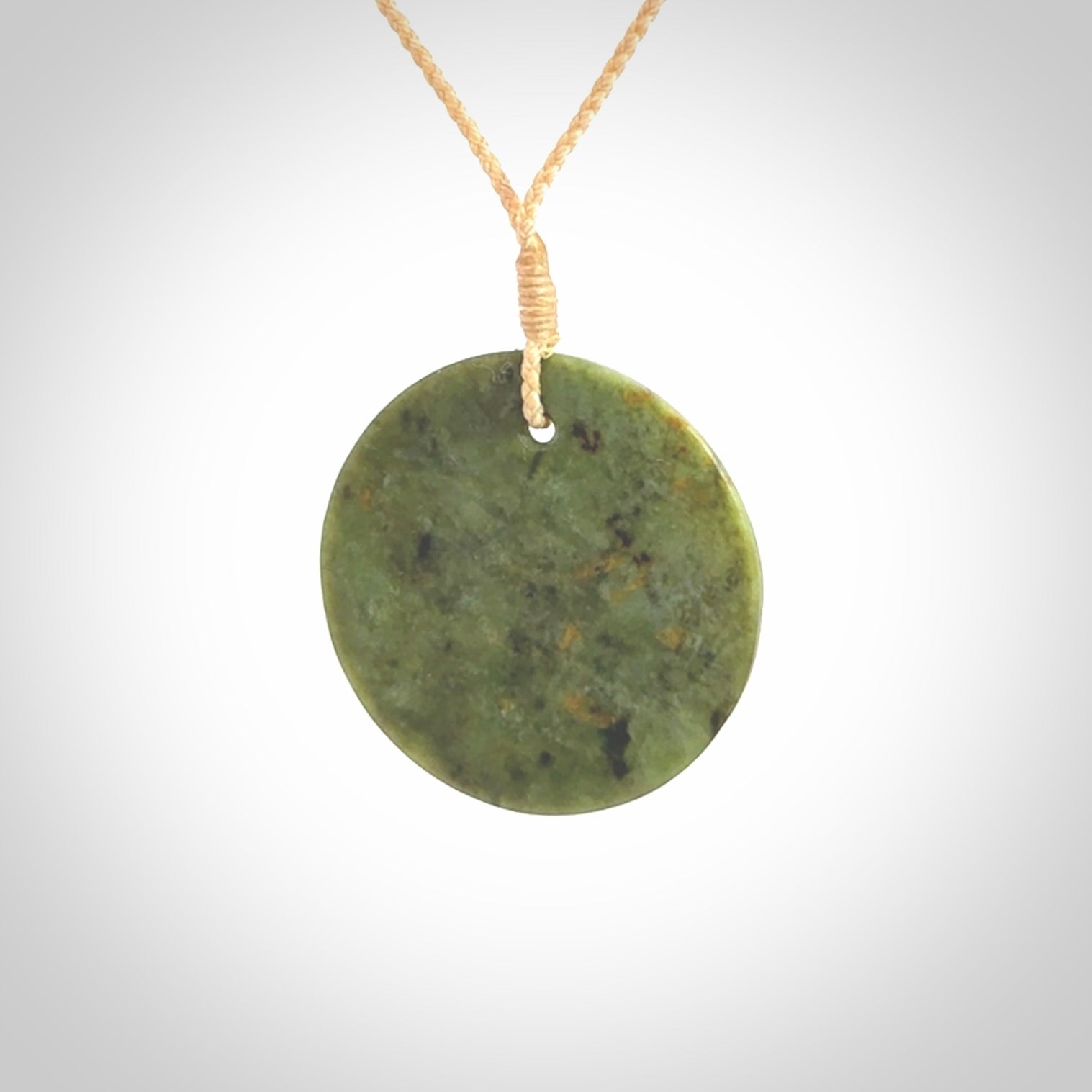 This piece is a medium sized, oval round, disc pendant. It is suspended on a beige coloured braided cord that is length adjustable.