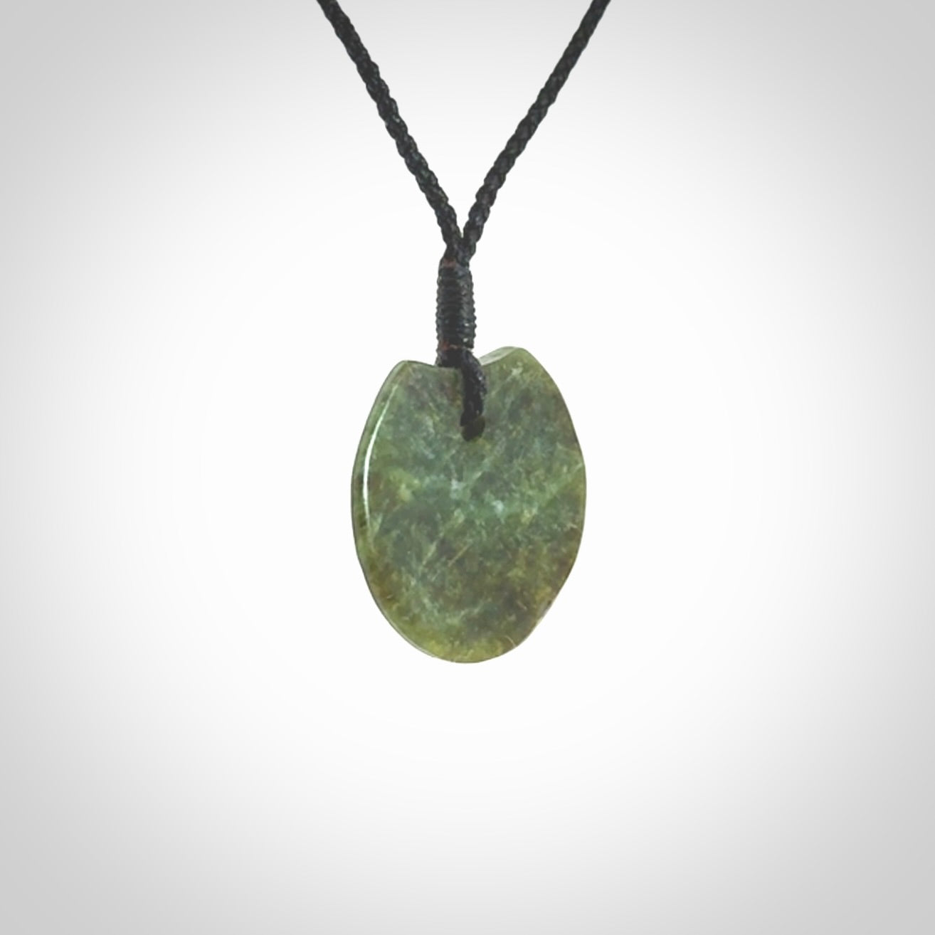 This piece is a small sized, oval round, disc pendant. It is suspended on a black coloured braided cord that is length adjustable.