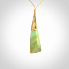 This photo shows a medium sized jade drop shaped pendant. It a a lovely varied green and light orange New Zealand Flower jade. The cord is a four plait beige and is adjustable in length.