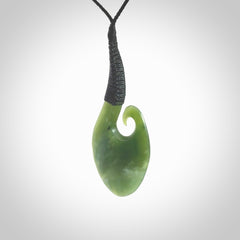 This picture shows a large deep green large jade koru pendant, also called a koru, carved for us in New Zealand jade. The cord is a four-plait, adjustable black coloured necklace.