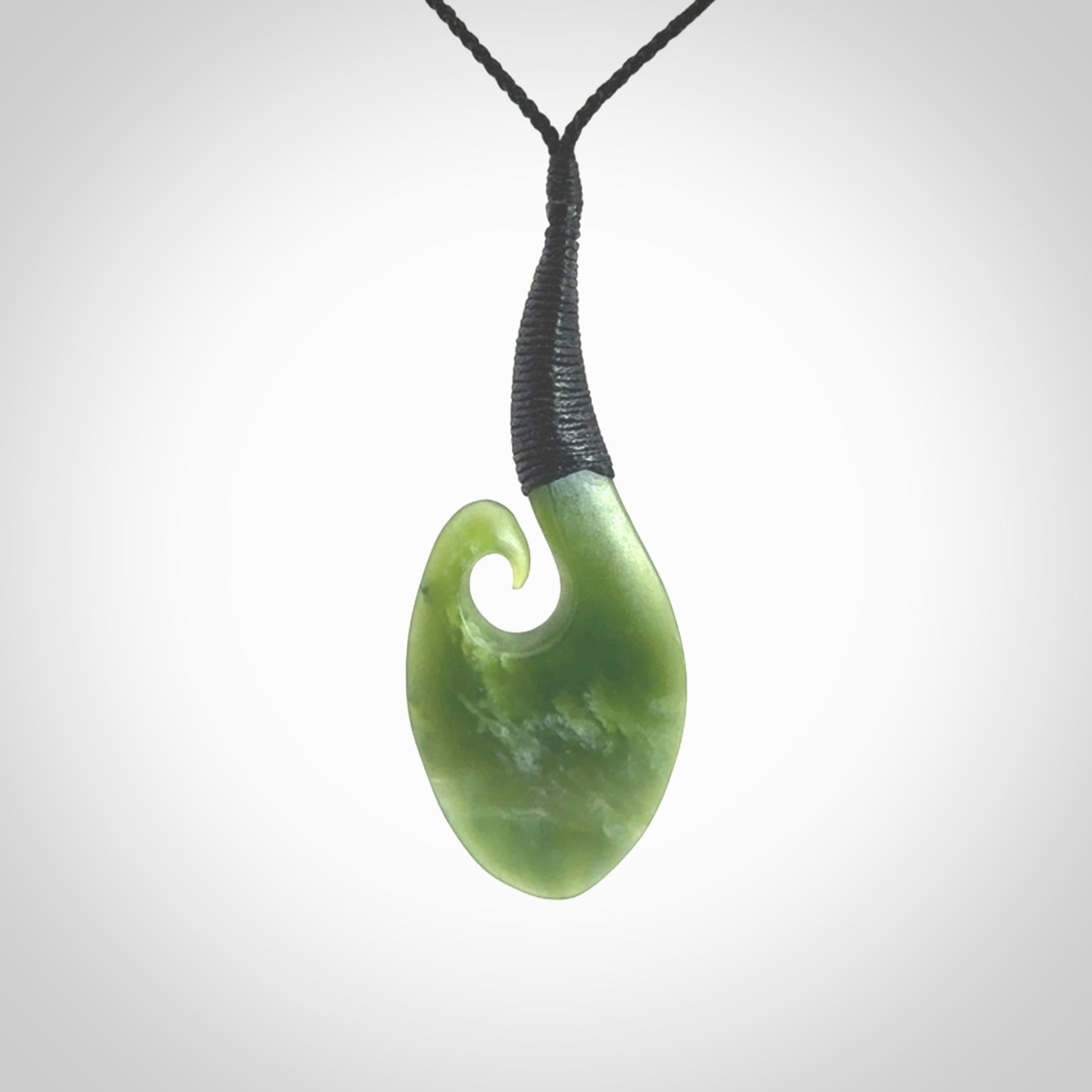 This picture shows a large deep green large jade koru pendant, also called a koru, carved for us in New Zealand jade. The cord is a four-plait, adjustable black coloured necklace.