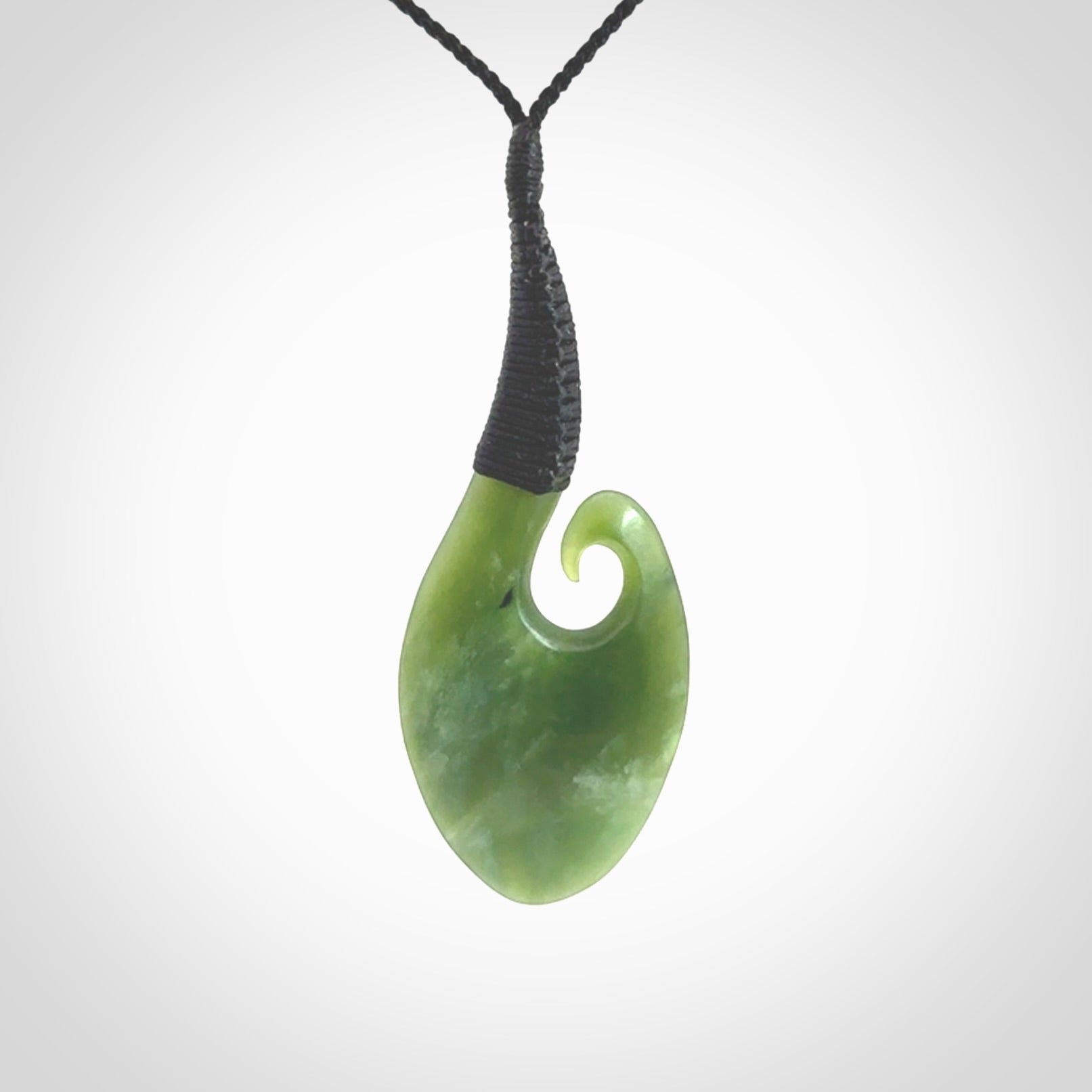 This picture shows a large deep green large jade koru pendant, also called a koru, carved for us in New Zealand jade. The cord is a four-plait, adjustable black coloured necklace.