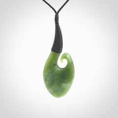 This picture shows a large deep green large jade koru pendant, also called a koru, carved for us in New Zealand jade. The cord is a four-plait, adjustable black coloured necklace.