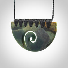 This picture shows a hand carved jade half-shield with Koru pendant. The cord is hand plaited and adjustable so that you can position the pendant where it suits you best.