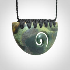 This picture shows a hand carved jade half-shield with Koru pendant. The cord is hand plaited and adjustable so that you can position the pendant where it suits you best.