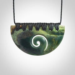 This picture shows a hand carved jade half-shield with Koru pendant. The cord is hand plaited and adjustable so that you can position the pendant where it suits you best.