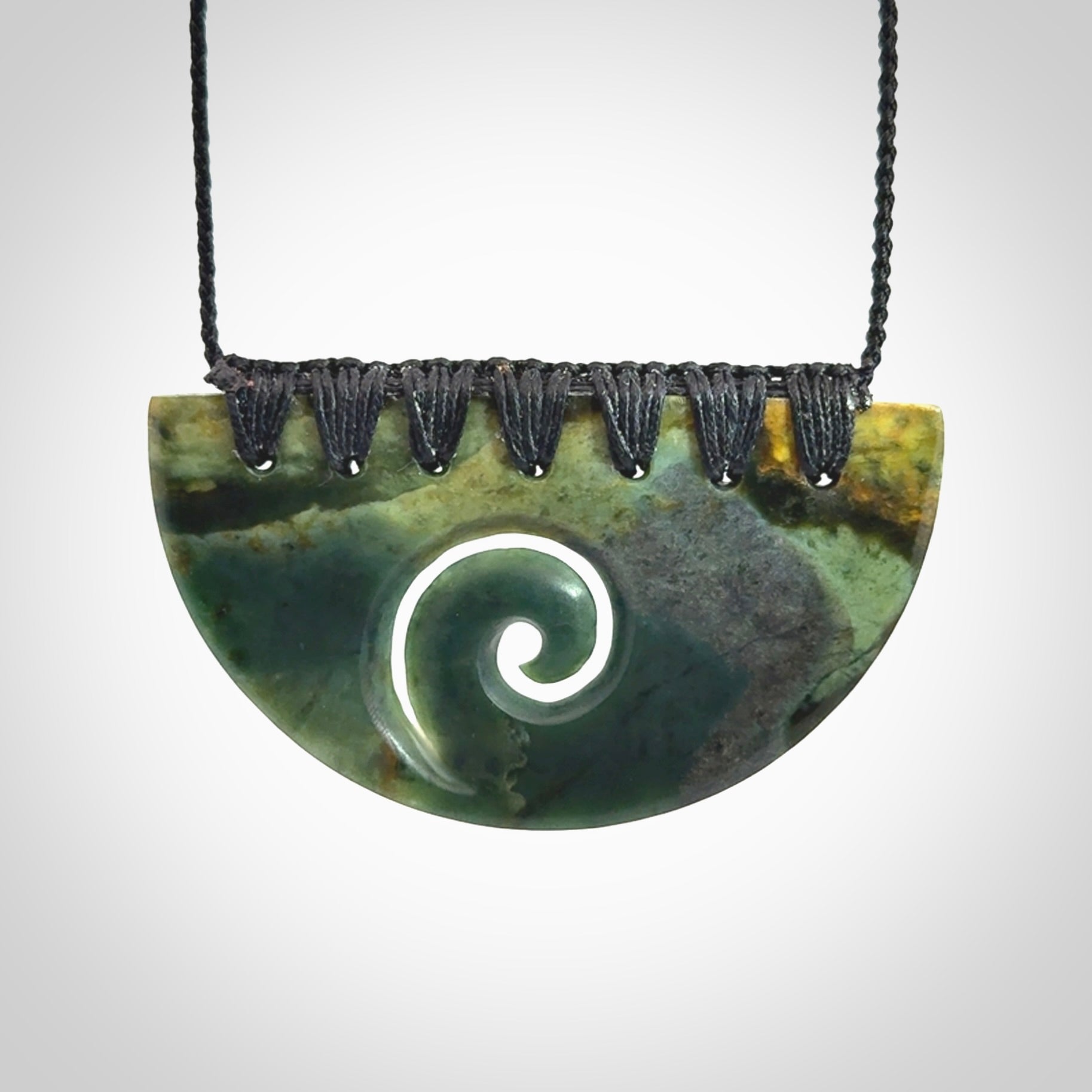 This picture shows a hand carved jade half-shield with Koru pendant. The cord is hand plaited and adjustable so that you can position the pendant where it suits you best.