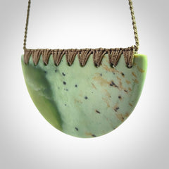 This picture shows a large, hand carved, jade half-shield pendant. The cord is hand plaited and adjustable so that you can position the pendant where it suits you best.