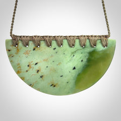 This picture shows a large, hand carved, jade half-shield pendant. The cord is hand plaited and adjustable so that you can position the pendant where it suits you best.