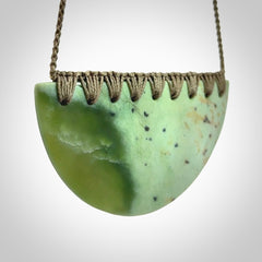 This picture shows a large, hand carved, jade half-shield pendant. The cord is hand plaited and adjustable so that you can position the pendant where it suits you best.