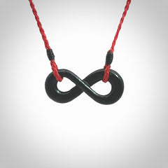 This piece is a fine, delicate eternity shaped pendant. It was carved from a lovely dark piece of black jade. It is suspended on an red braided cord that is length adjustable.