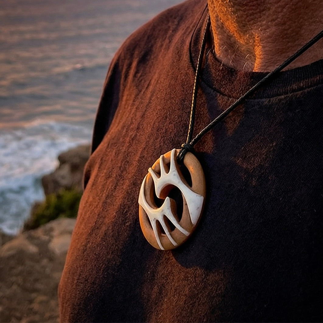 A hand carved bone contemporary, intricate pendant. The cord is a black colour and is a fixed length. A medium sized hand made contemporary necklace by New Zealand artist Kerry Thompson. Kerry has stained parts of the bone which really add to the dimension of this pendant. One off work of art to wear.