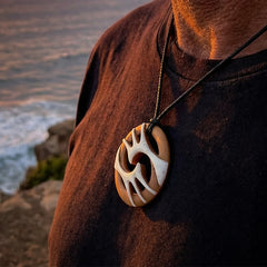 A hand carved bone contemporary, intricate pendant. The cord is a black colour and is a fixed length. A medium sized hand made contemporary necklace by New Zealand artist Kerry Thompson. Kerry has stained parts of the bone which really add to the dimension of this pendant. One off work of art to wear.