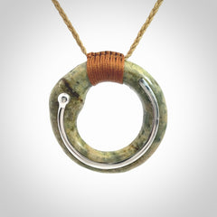 This picture shows a hand carved Nephrite jade circle pendant with sterling silver inlay. It is suspended from an adjustable coloured cord. Delivery is free worldwide.