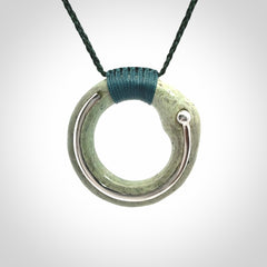 This picture shows a hand carved Nephrite jade zen circle pendant with sterling silver inlay. It is suspended from an adjustable cord.