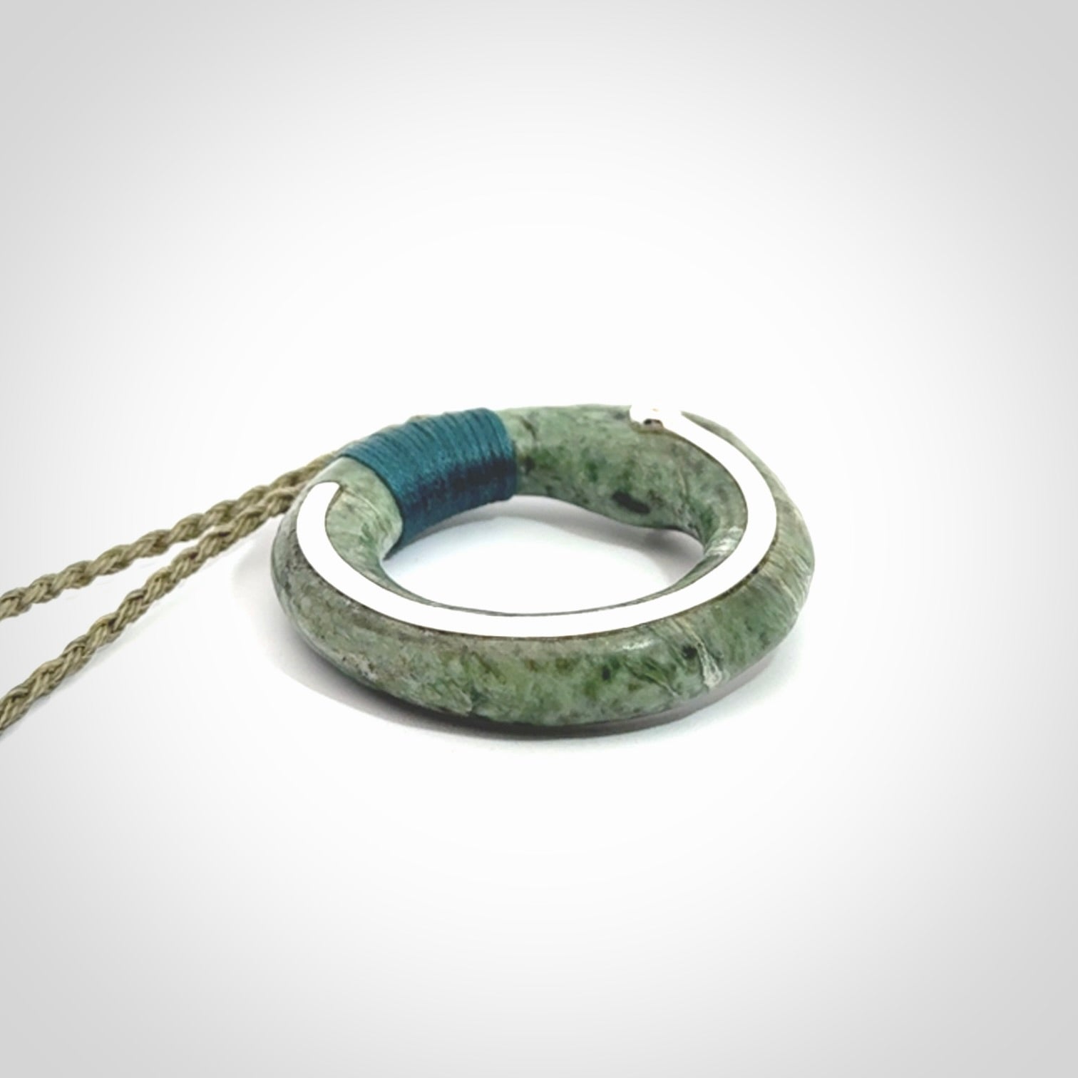 This picture shows a hand carved Nephrite jade circle pendant with sterling silver inlay. It is suspended from an adjustable coloured cord. Delivery is free worldwide.