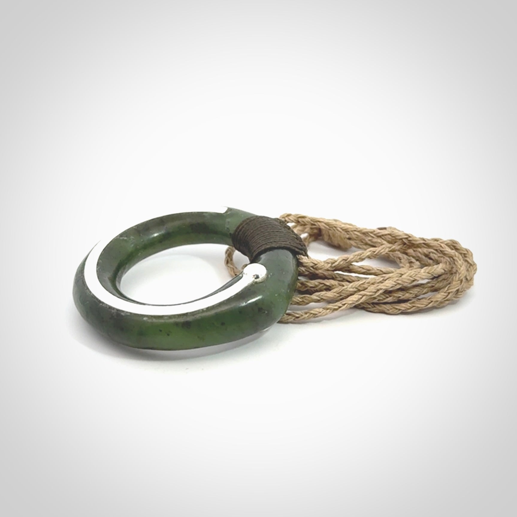 This picture shows a hand carved Nephrite jade circle pendant with sterling silver inlay. It is suspended from an adjustable Kalahari coloured cord. Delivery is free worldwide.