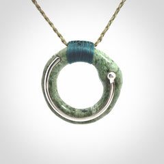 This picture shows a hand carved Nephrite jade circle pendant with sterling silver inlay. It is suspended from an adjustable coloured cord. Delivery is free worldwide.