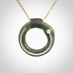 This picture shows a hand carved Nephrite jade circle pendant with sterling silver inlay. It is suspended from an adjustable Kalahari coloured cord. Delivery is free worldwide.