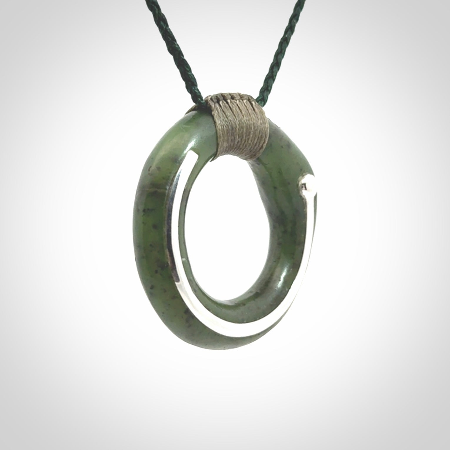 This picture shows a hand carved Nephrite jade zen circle pendant with sterling silver inlay. It is suspended from an adjustable cord.