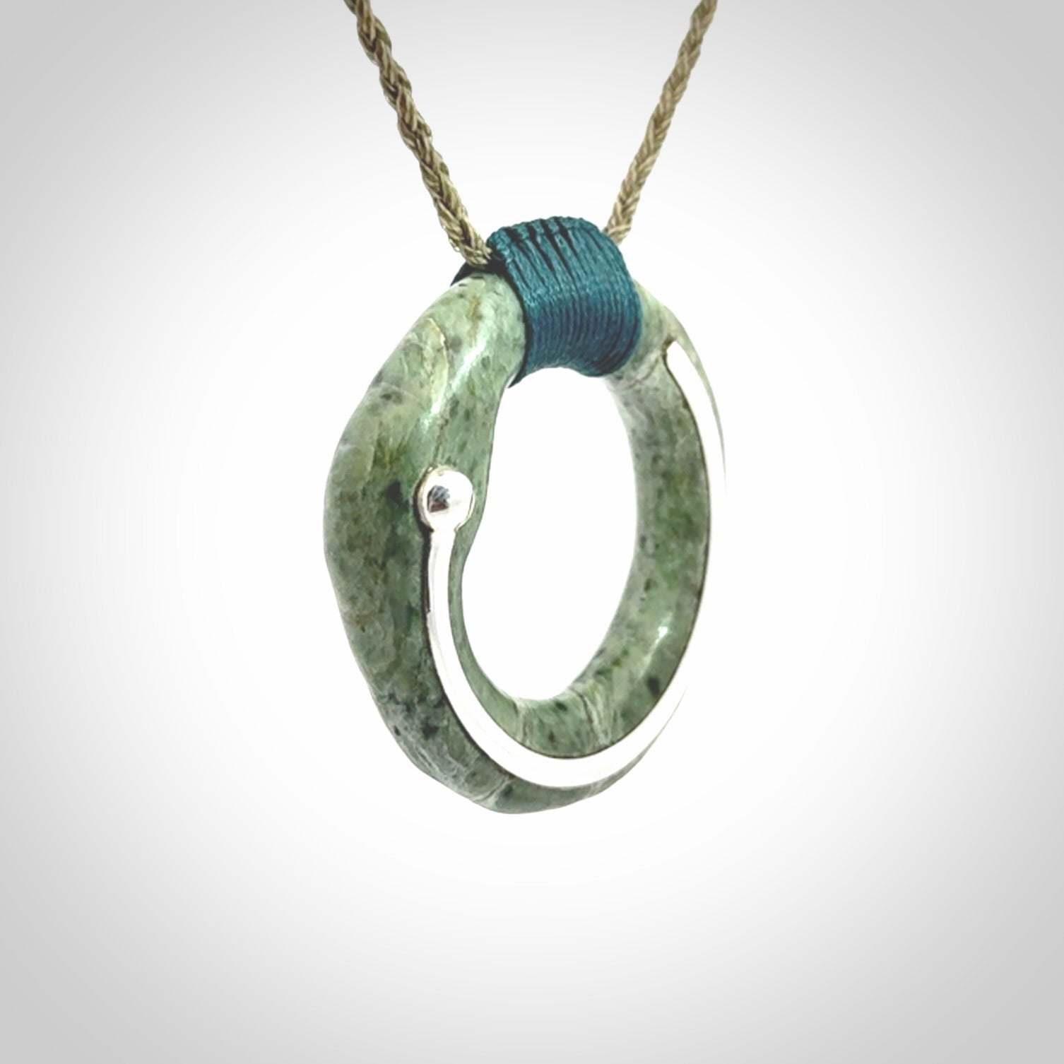 This picture shows a hand carved Nephrite jade circle pendant with sterling silver inlay. It is suspended from an adjustable coloured cord. Delivery is free worldwide.