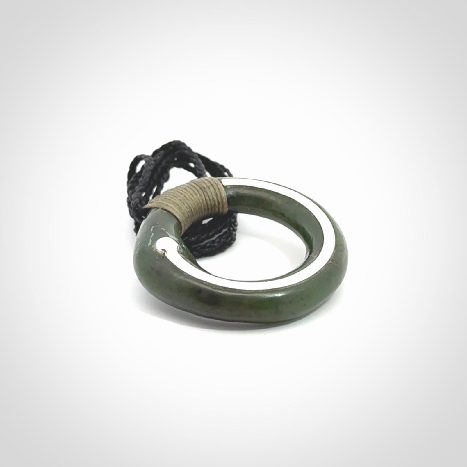 This picture shows a hand carved Nephrite jade zen circle pendant with sterling silver inlay. It is suspended from an adjustable cord.