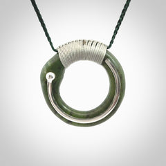 This picture shows a hand carved Nephrite jade circle pendant with sterling silver inlay. It is suspended from an adjustable coloured cord. Delivery is free worldwide.