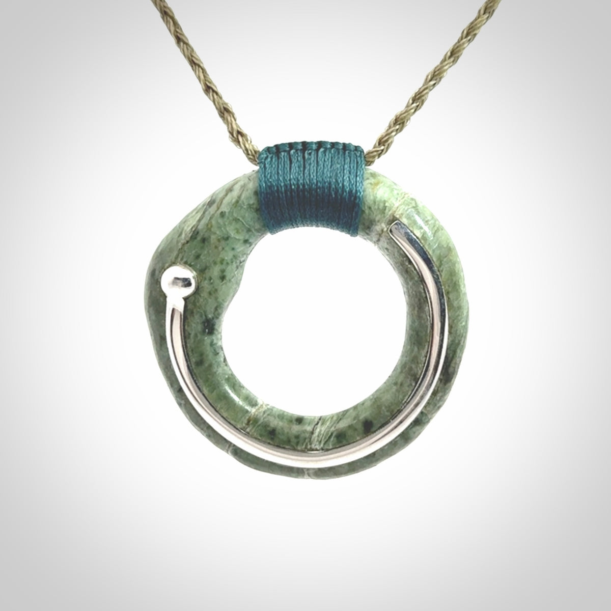 This picture shows a hand carved Nephrite jade circle pendant with sterling silver inlay. It is suspended from an adjustable coloured cord. Delivery is free worldwide.