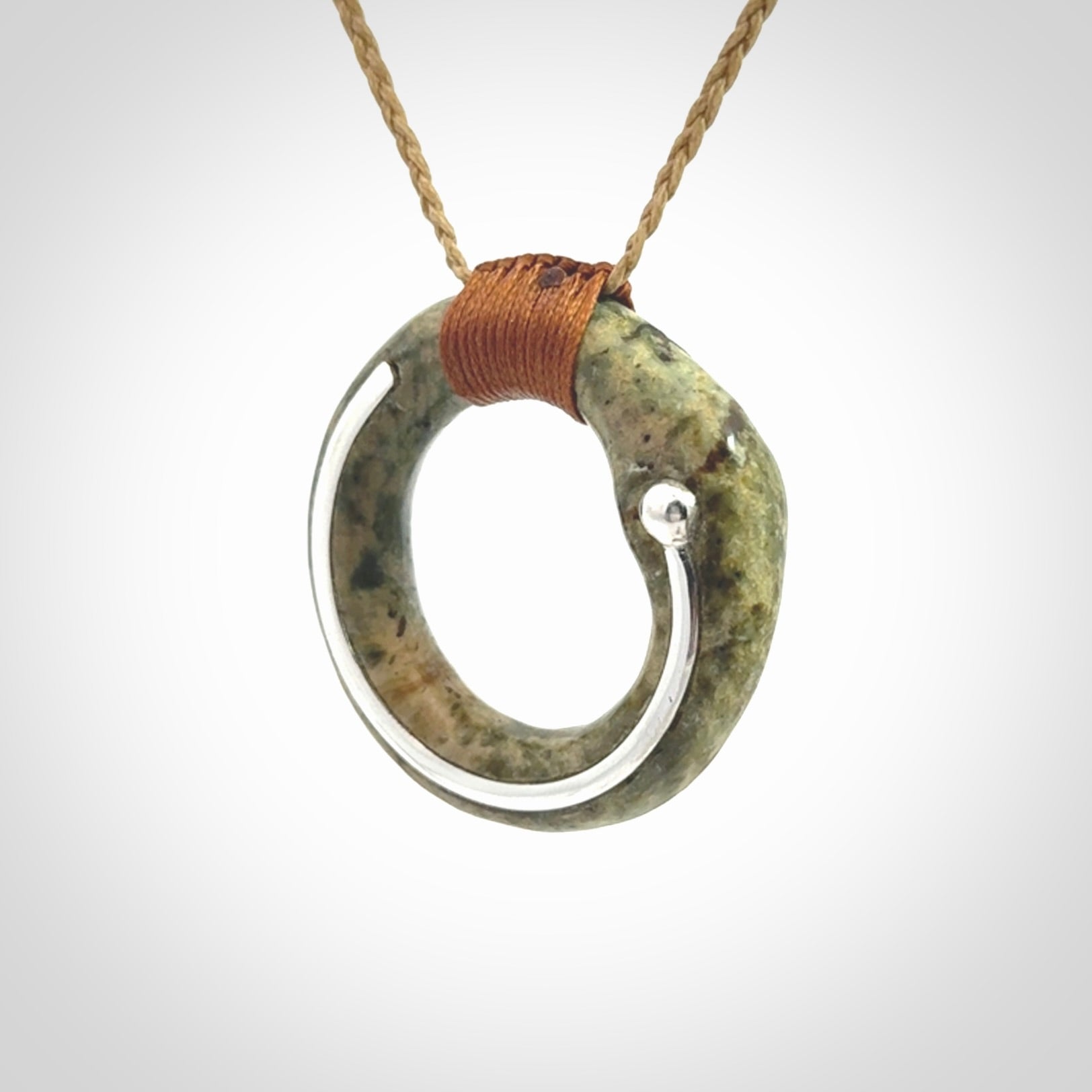 This picture shows a hand carved Nephrite jade circle pendant with sterling silver inlay. It is suspended from an adjustable coloured cord. Delivery is free worldwide.