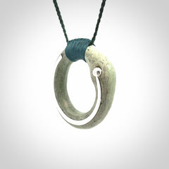This picture shows a hand carved Nephrite jade zen circle pendant with sterling silver inlay. It is suspended from an adjustable cord.