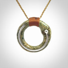 This picture shows a hand carved Nephrite jade circle pendant with sterling silver inlay. It is suspended from an adjustable coloured cord. Delivery is free worldwide.
