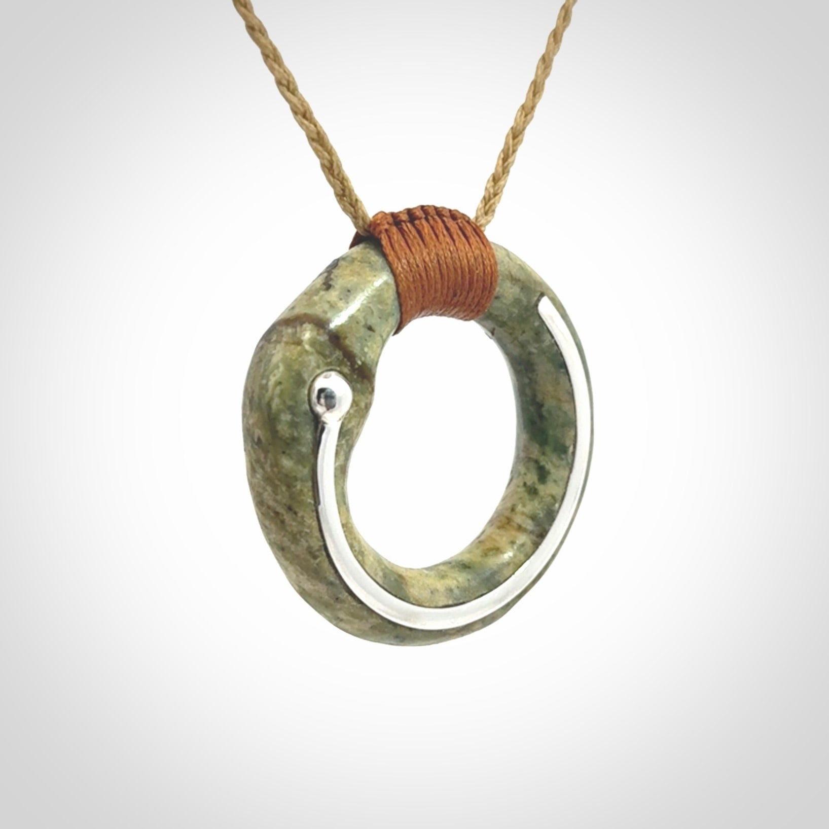 This picture shows a hand carved Nephrite jade circle pendant with sterling silver inlay. It is suspended from an adjustable coloured cord. Delivery is free worldwide.
