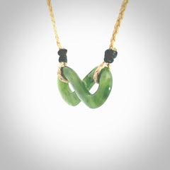 This piece is a fine, delicate eternity shaped pendant. It was carved from a lovely green piece of British Columbian jade. It is suspended on an oat coloured cord that is length adjustable.