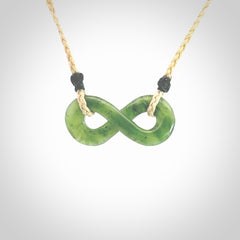 This piece is a fine, delicate eternity shaped pendant. It was carved from a lovely green piece of British Columbian jade. It is suspended on an oat coloured cord that is length adjustable.
