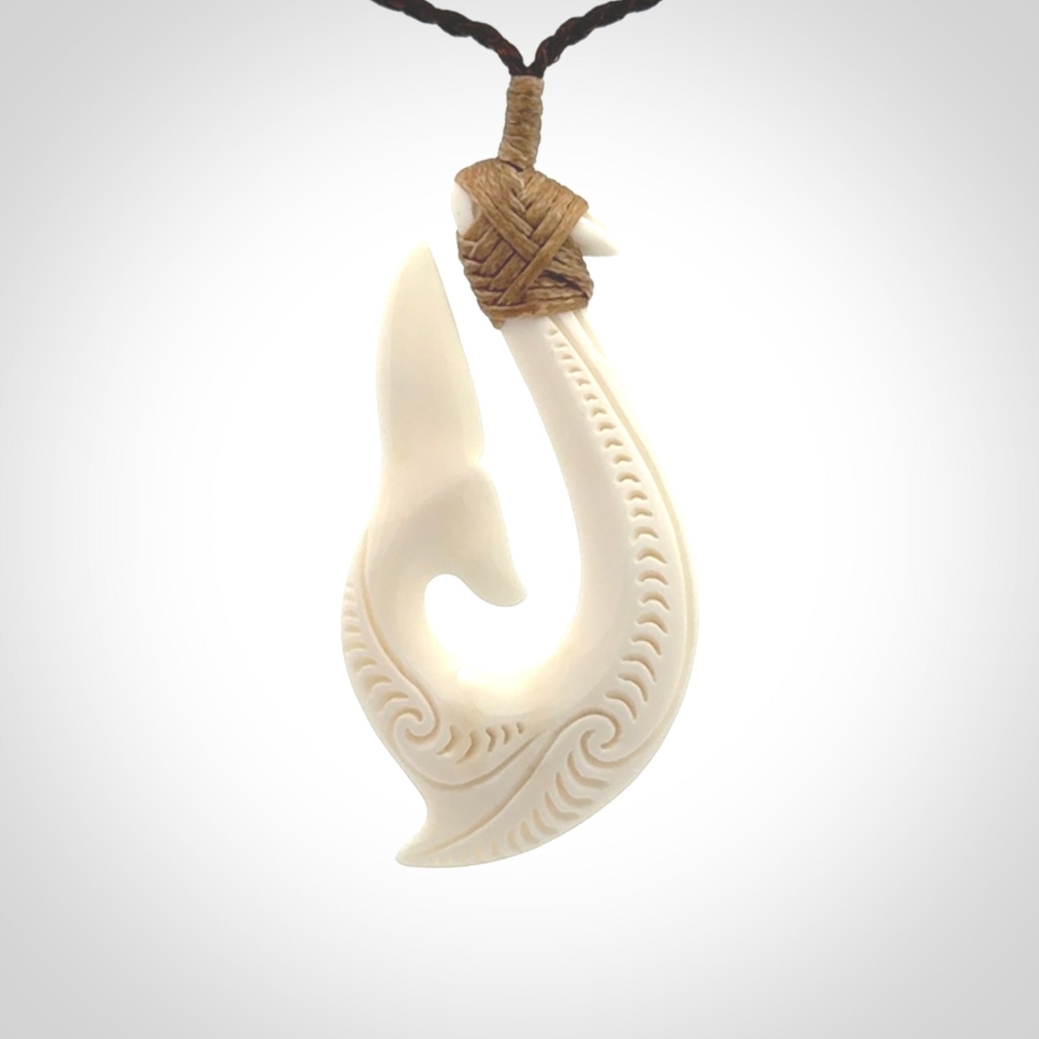 A handcarved hook pendant with a whaletail end. This is carved from bone and is detailed with a traditional Maori engraved design. We will ship this piece to you anywhere in the world and the price for shipping is included in the price. Unique bone jewellery for sale online at www.nzpacific.com