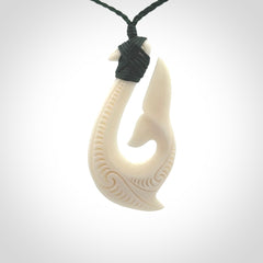 A handcarved hook pendant with a whaletail end. This is carved from bone and is detailed with a traditional Maori engraved design. We will ship this piece to you anywhere in the world and the price for shipping is included in the price. Unique bone jewellery for sale online at www.nzpacific.com