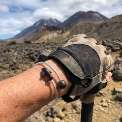 Hand wearing a bracelet with a mountainous landscape in the background