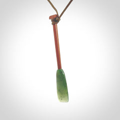 This pendant is a hand carved dragon boat paddle. We have carved this with a Green Nephrite jade blade and a hardwood handle. It is a necklace that was carved for suffered of breast cancer who are members of the Pink Dragons, a group or cancer fighters who take part in Dragon Boat racing events around the world.