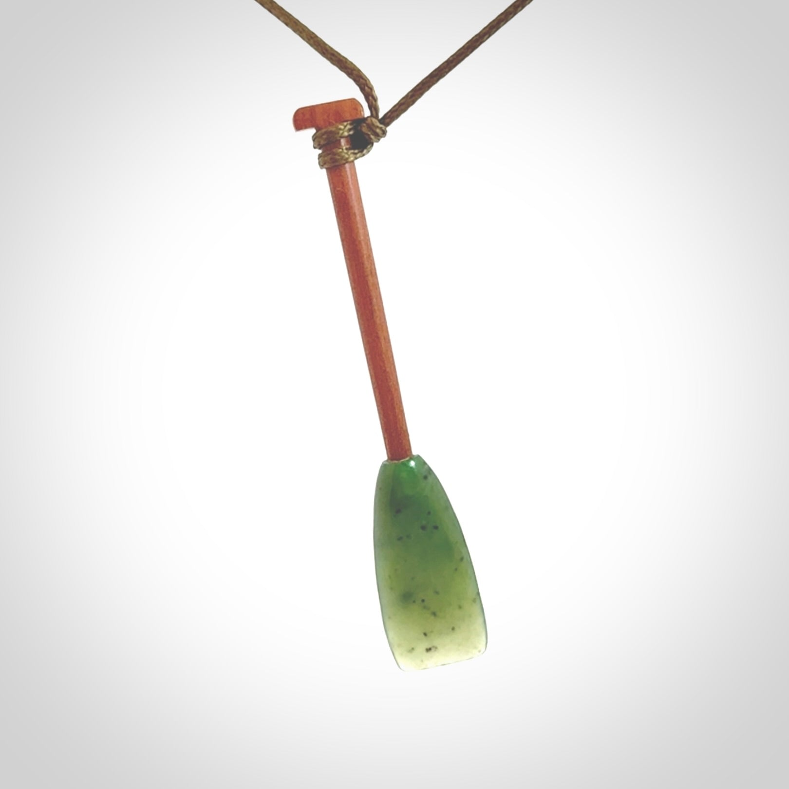 This pendant is a hand carved dragon boat paddle. We have carved this with a Green Nephrite jade blade and a hardwood handle. It is a necklace that was carved for suffered of breast cancer who are members of the Pink Dragons, a group or cancer fighters who take part in Dragon Boat racing events around the world.