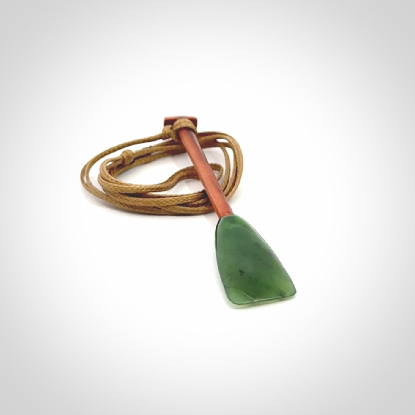 This pendant is a hand carved dragon boat paddle. We have carved this with a Green Nephrite jade blade and a hardwood handle. It is a necklace that was carved for suffered of breast cancer who are members of the Pink Dragons, a group or cancer fighters who take part in Dragon Boat racing events around the world.