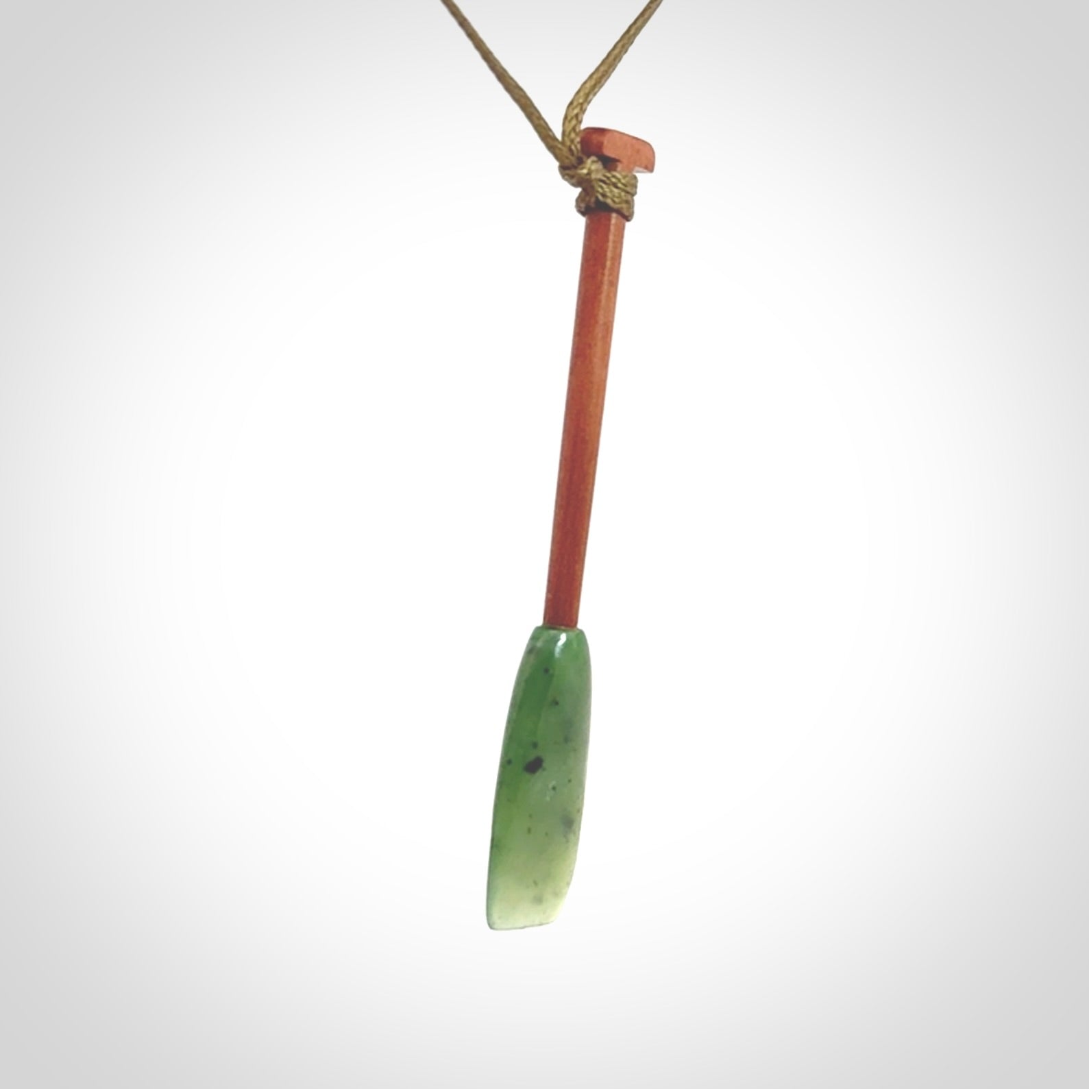 This pendant is a hand carved dragon boat paddle. We have carved this with a Green Nephrite jade blade and a hardwood handle. It is a necklace that was carved for suffered of breast cancer who are members of the Pink Dragons, a group or cancer fighters who take part in Dragon Boat racing events around the world.