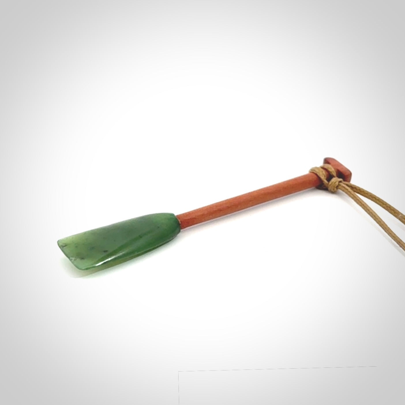 This pendant is a hand carved dragon boat paddle. We have carved this with a Green Nephrite jade blade and a hardwood handle. It is a necklace that was carved for suffered of breast cancer who are members of the Pink Dragons, a group or cancer fighters who take part in Dragon Boat racing events around the world.