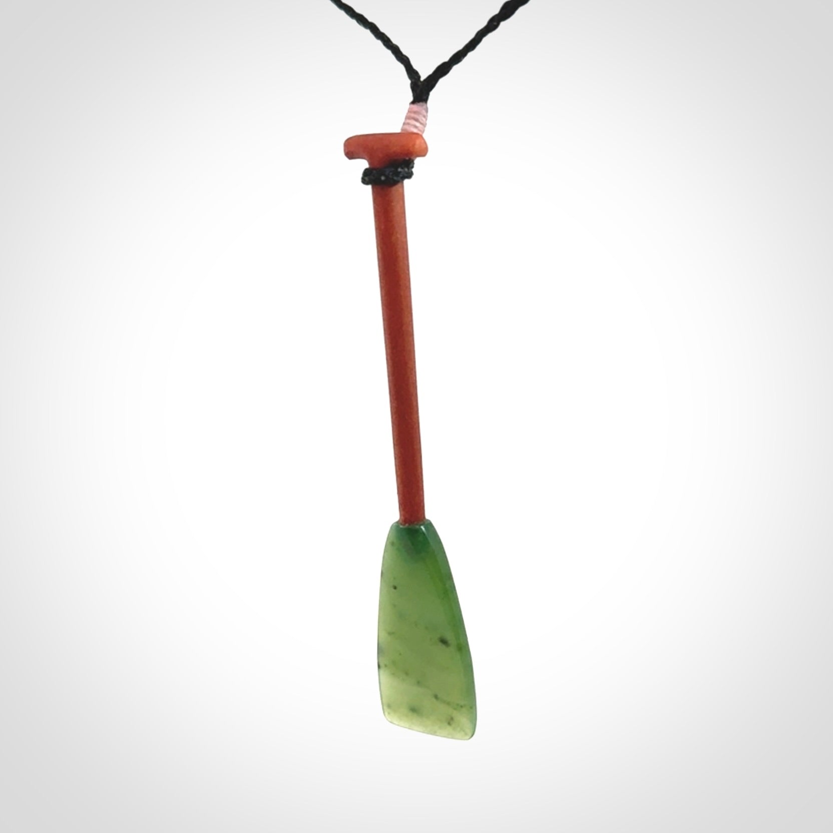 This pendant is a hand carved dragon boat paddle. We have carved this with a Green Nephrite jade blade and a hardwood handle. It is a necklace that was carved for suffered of breast cancer who are members of the Pink Dragons, a group or cancer fighters who take part in Dragon Boat racing events around the world.
