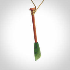 This pendant is a hand carved dragon boat paddle. We have carved this with a Green Nephrite jade blade and a hardwood handle. It is a necklace that was carved for suffered of breast cancer who are members of the Pink Dragons, a group or cancer fighters who take part in Dragon Boat racing events around the world.